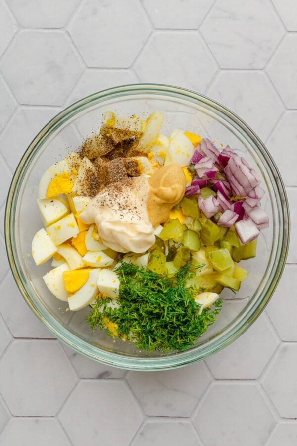 Egg salad ingredients in a glass bowl before being mixed up.
