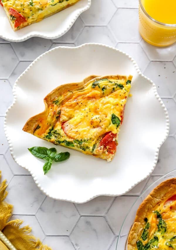 Healthy egg and veggie egg bake with tortilla crust slice on a plate with more behind it.