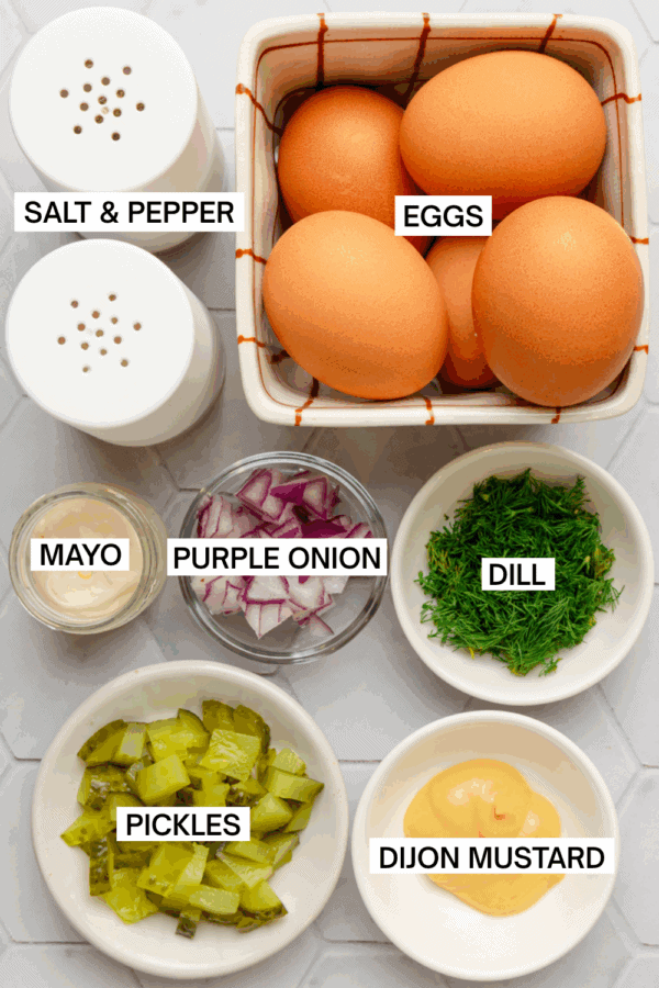 Ingredients for healthy egg salad in bowls with labels over each ingredient.