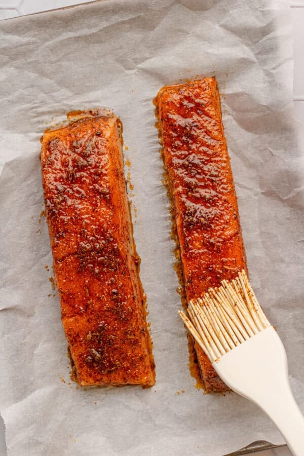 Brushing Cajun seasoning on uncooked salmon filets.