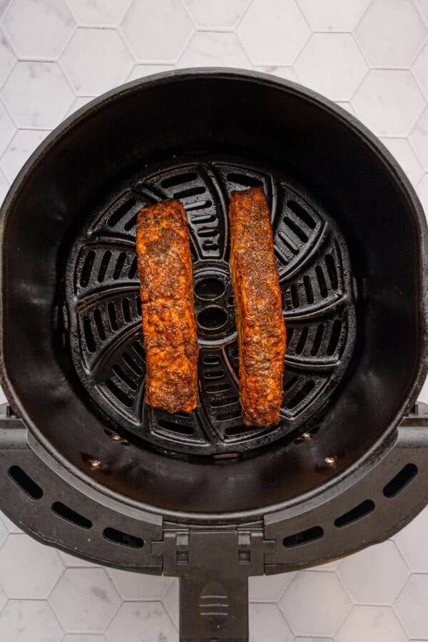 Air fried cajun salmon filets in air fryer basket.