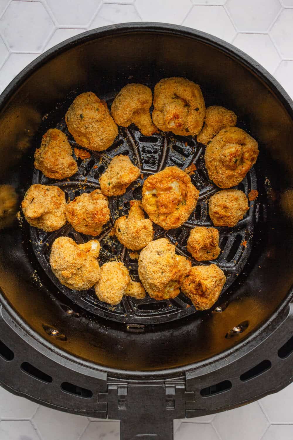 Crispy cooked breaded cauliflower bites in an air fryer basket.