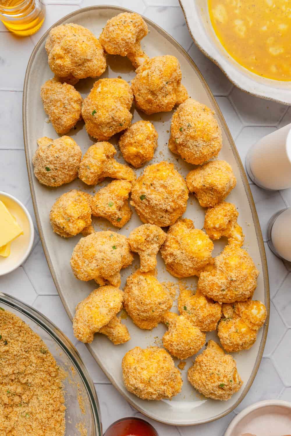 Tray of coated uncooked breaded cauliflower florets.