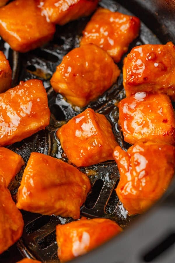 Cooked seasoned salmon cubes in an air fryer basket.