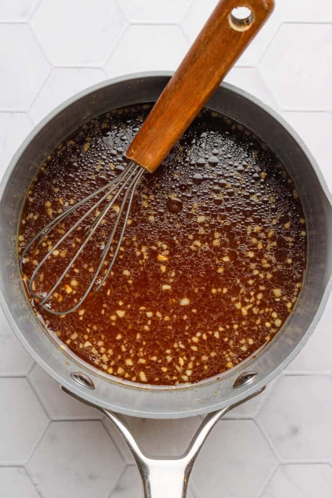 Teriyaki sauce cooked in a pot with a whisk in the pot.