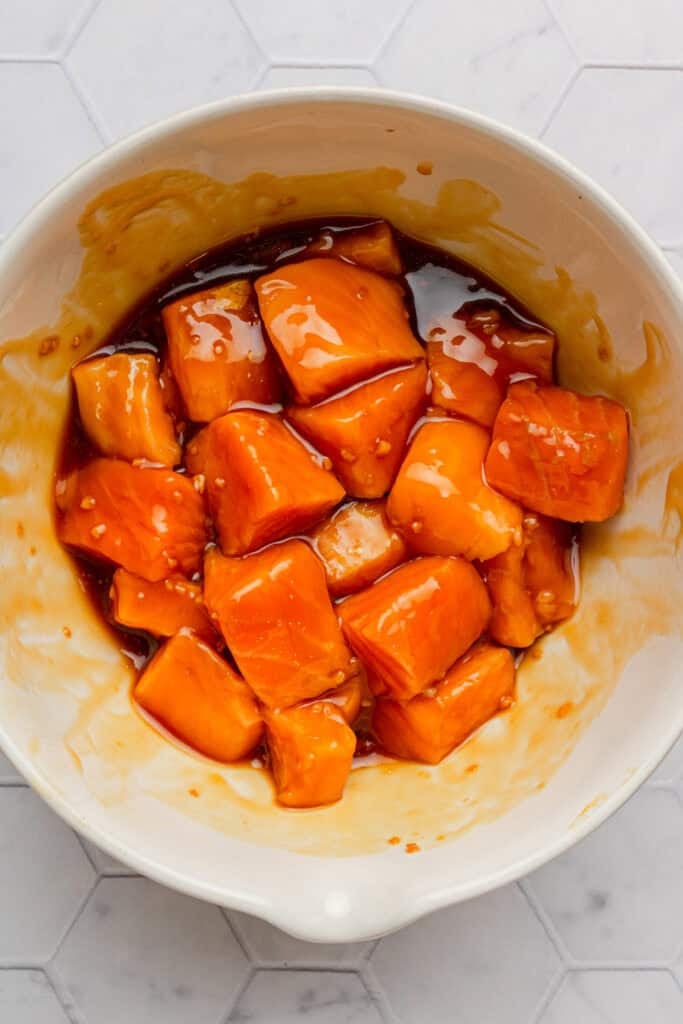 Marinated uncooked cubed salmon in a bowl.