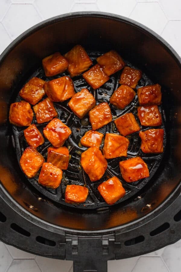 Air fried teriyaki salmon bites in an air fryer basket.