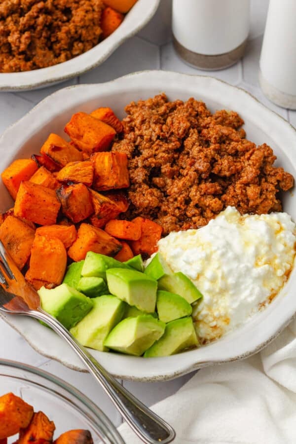 bowl filled with cooked sweet potato, cubed avocado, cottage cheese and cooked ground beef.