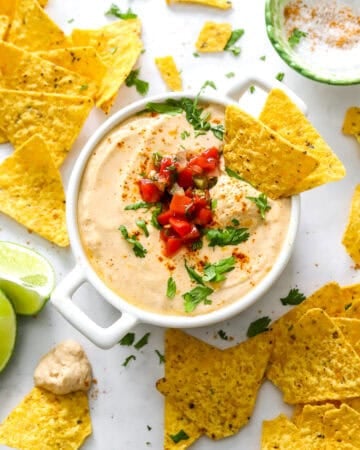 Queso with cottage cheese in a white dish with chips around it.
