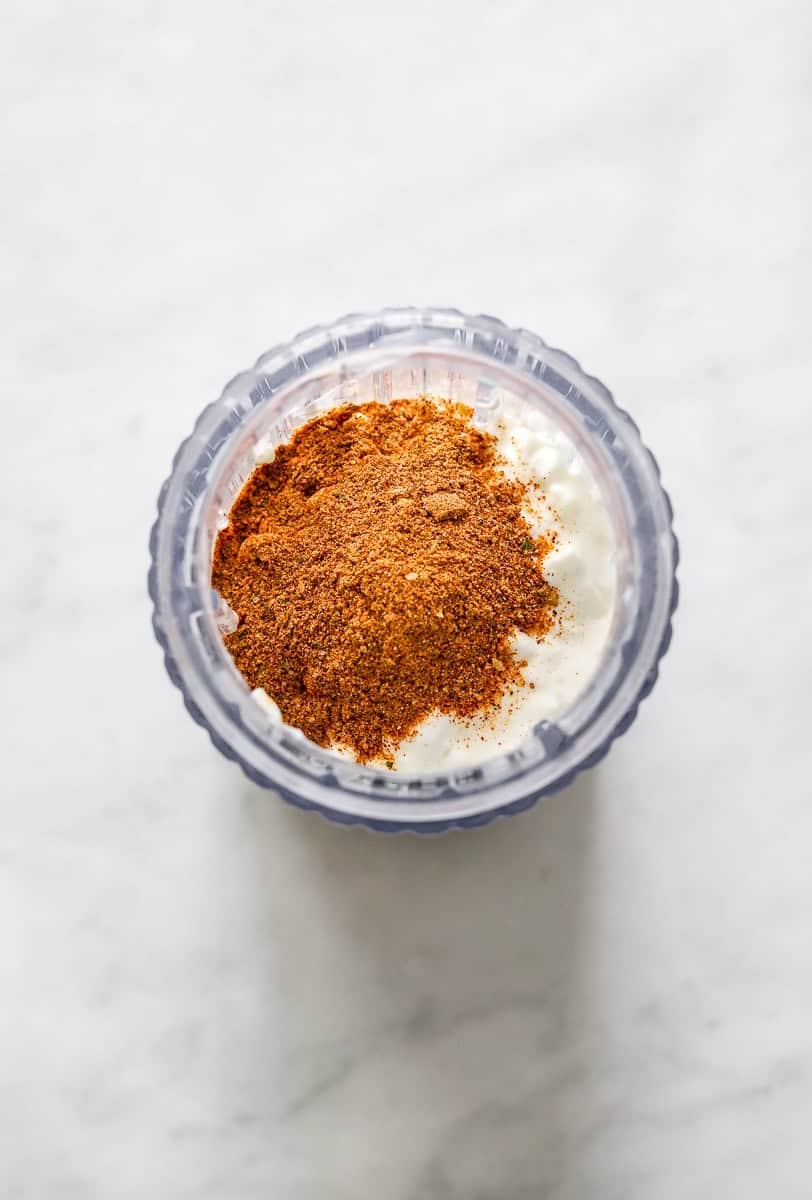 Cottage cheese and taco seasoning in a blender bottle before being blended.