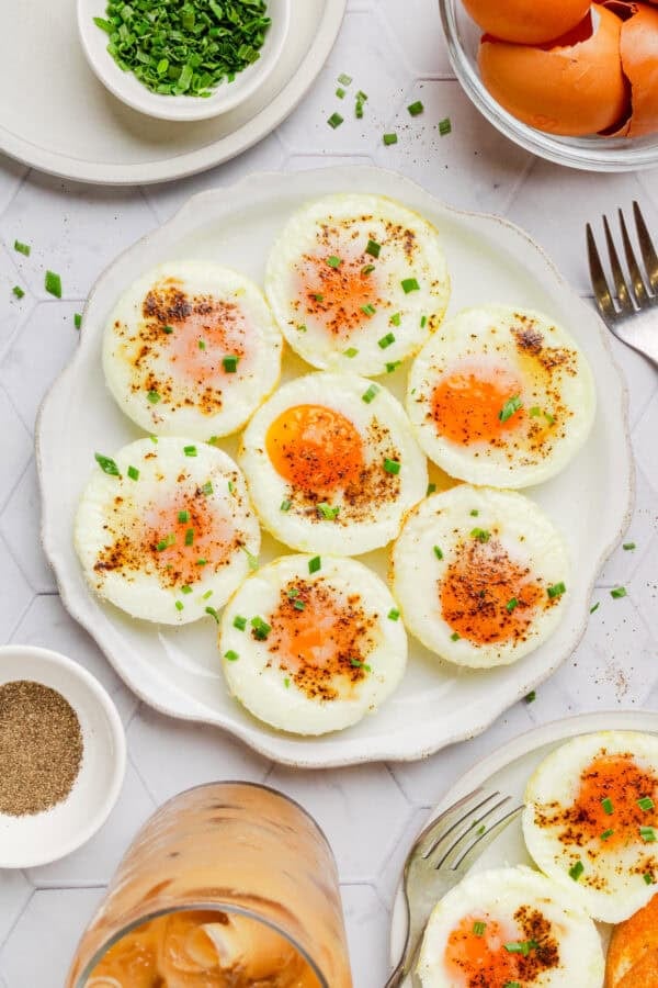 Plate of whole baked eggs with more ingredients around it.