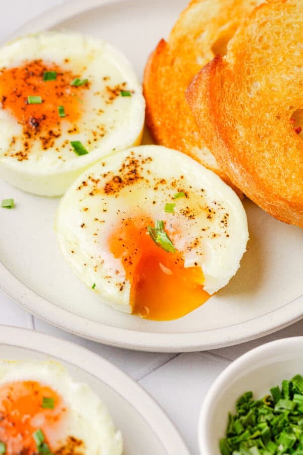 Oven baked egg with the yolk coming out of it with more baked eggs around it.