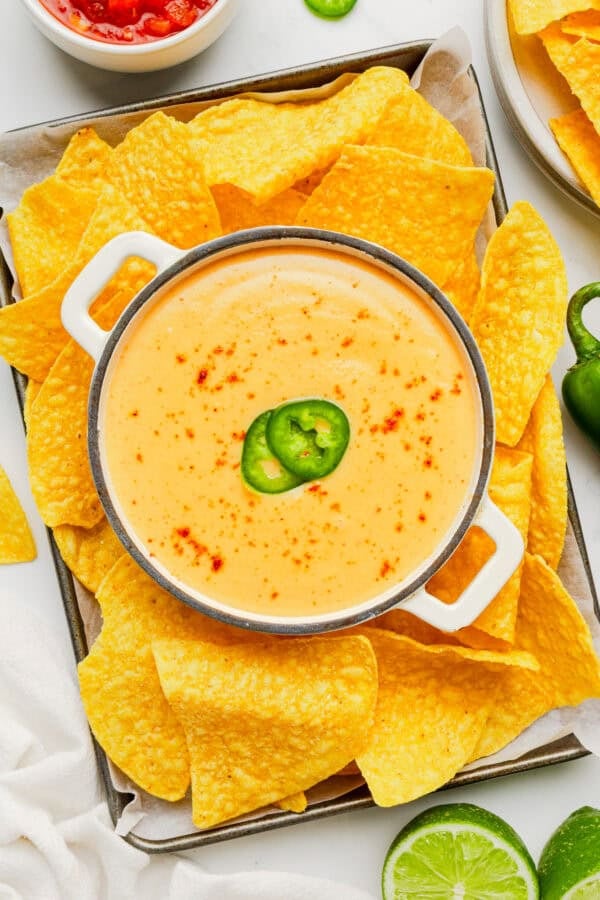 Platter of chips and queso sauce in a pot in the middle of the platter.