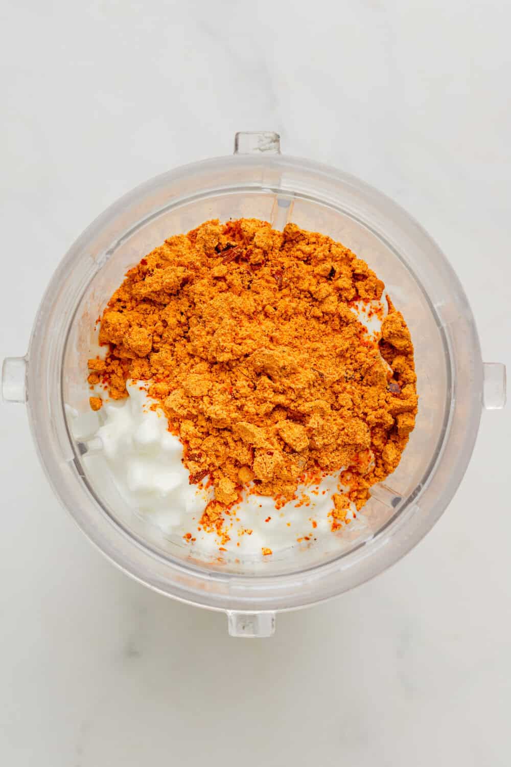 Cottage cheese and taco seasoning in a blender before being blended.