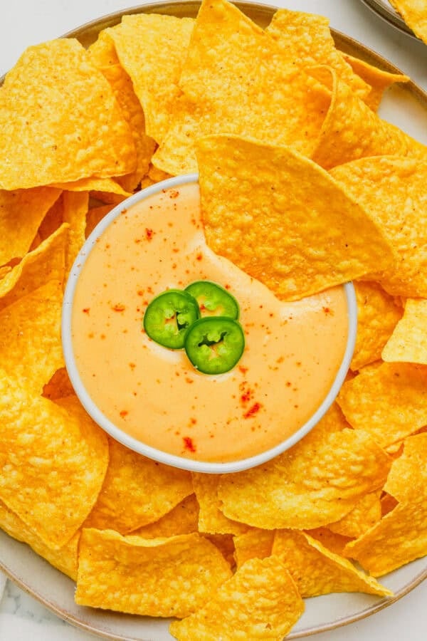 Platter of tortilla chips with a bowl of queso in the middle of the platter.