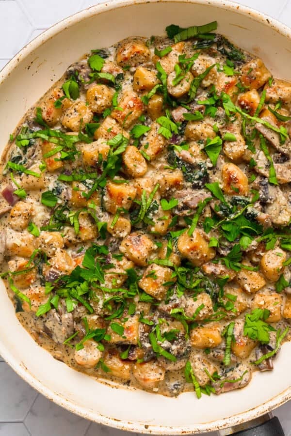 Cauliflower gnocchi from Trader Joes cooked in a spinach cream sauce in a pan.
