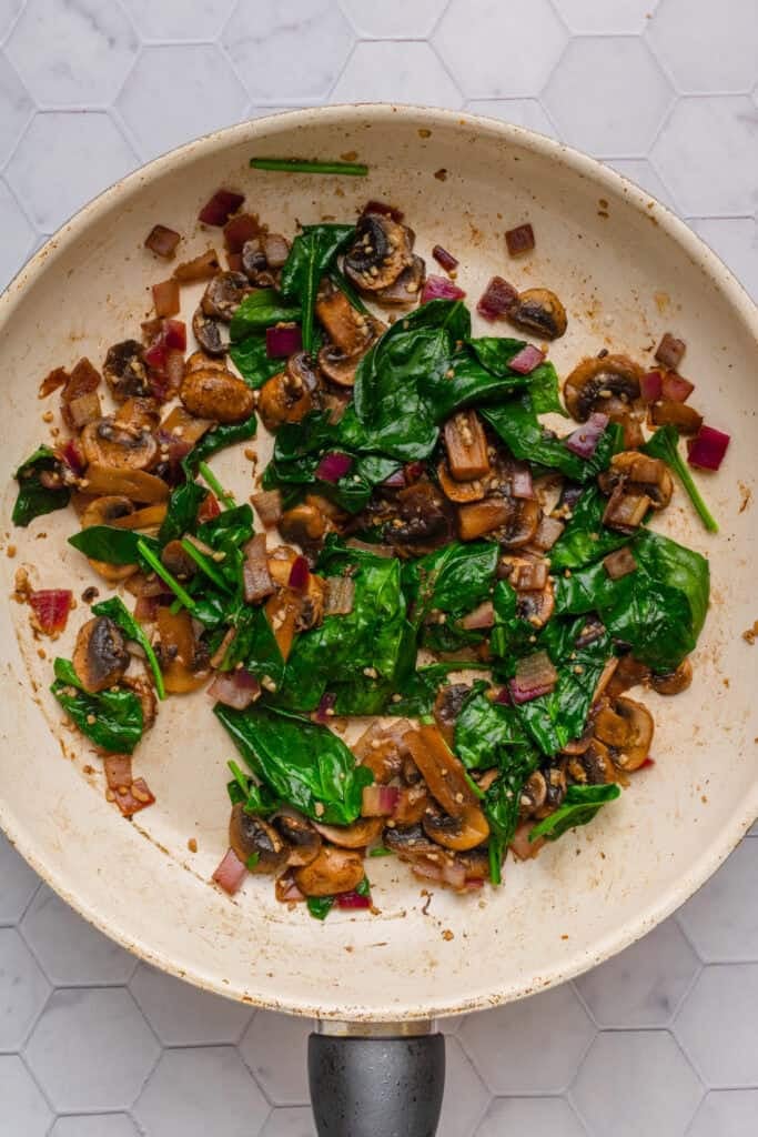 Spinach and mushrooms sautéed in a pan. 