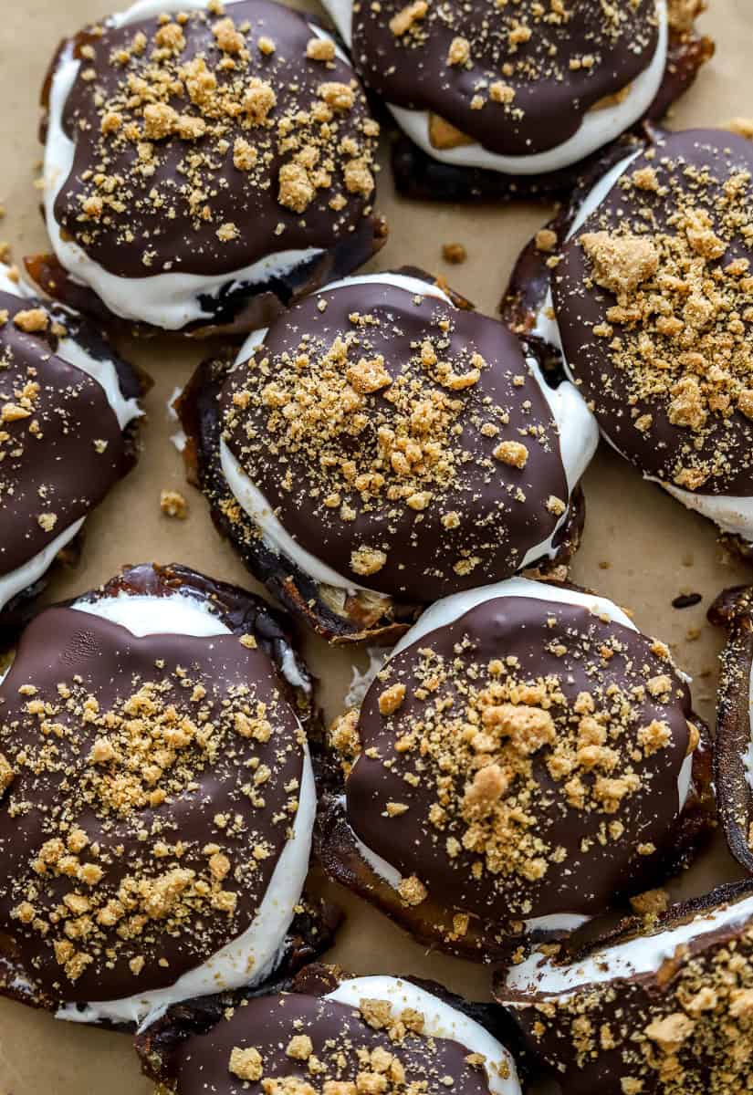 Pressed dates topped with marshmallow fluff, graham crackers and melted chocolate with more around it.
