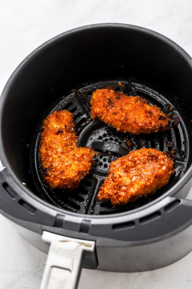 Cooked breaded crispy chicken in an air fryer basket. 
