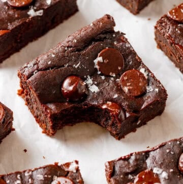 Avocado black bread brownie with a bite taken out of it with more brownies around it.
