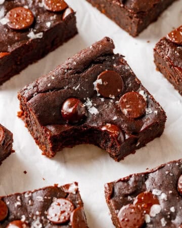 Avocado black bread brownie with a bite taken out of it with more brownies around it.