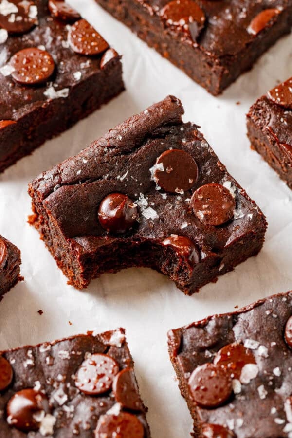 Avocado black bread brownie with a bite taken out of it with more brownies around it.