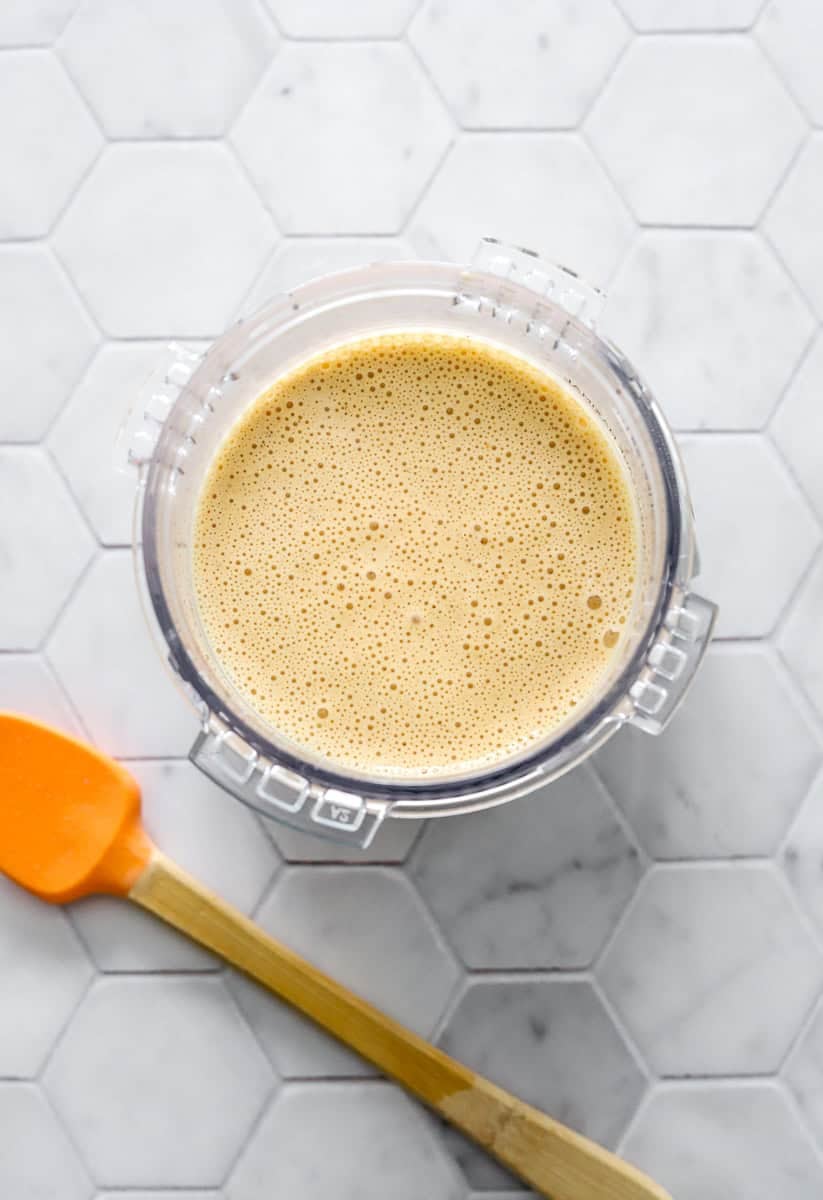 Pint container with blended pumpkin ice cream mixture in it with an orange and wood mini spatula in front of it.