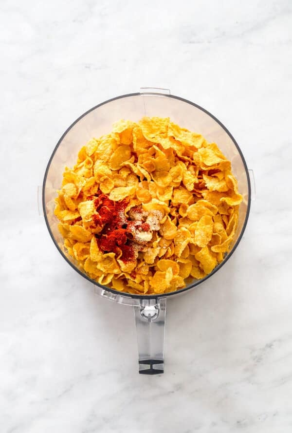 Cornflakes and seasoning in the bowl of food processor before being blended.