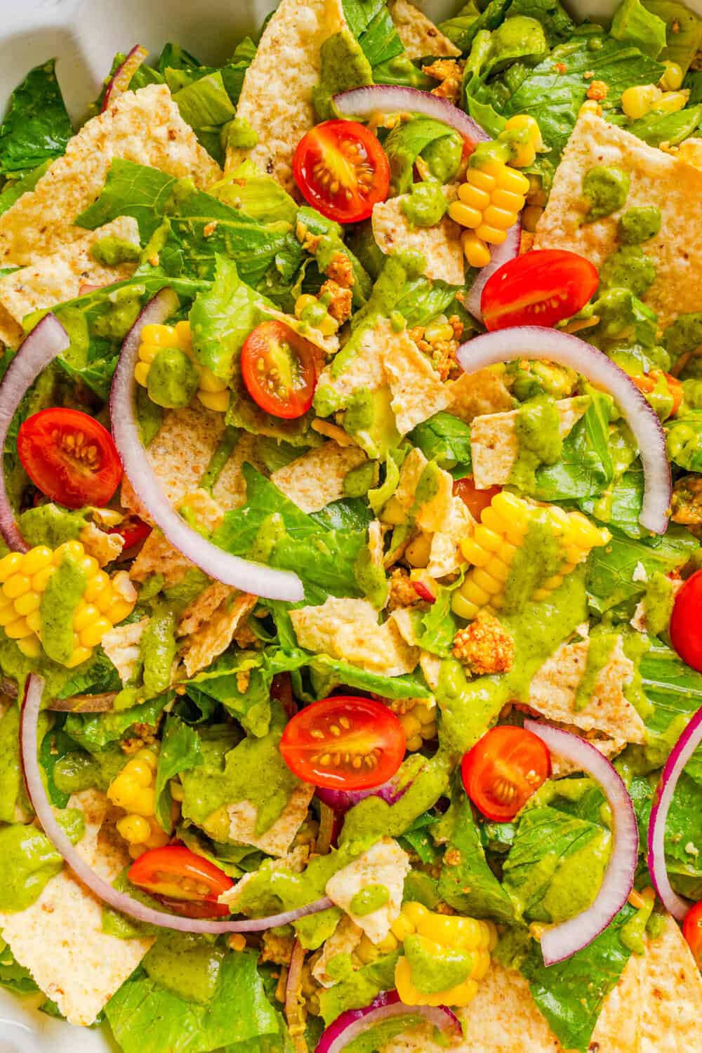 Salad with cooked taco ground chicken, tomato, onion, corn, tortilla chips and lime dressing mixed together. 
