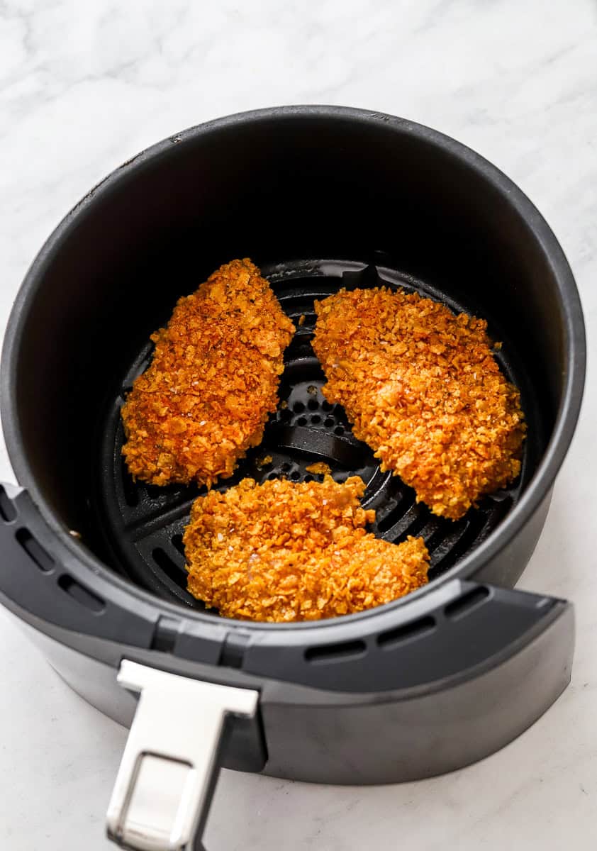 Uncooked coated chicken in an air fryer basket. 