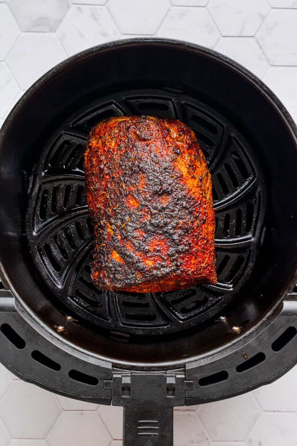Air fried golden pork loin in the air fryer basket. 