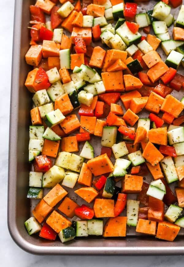 Un cooked, cut, seasoned vegetables on a baking sheet.