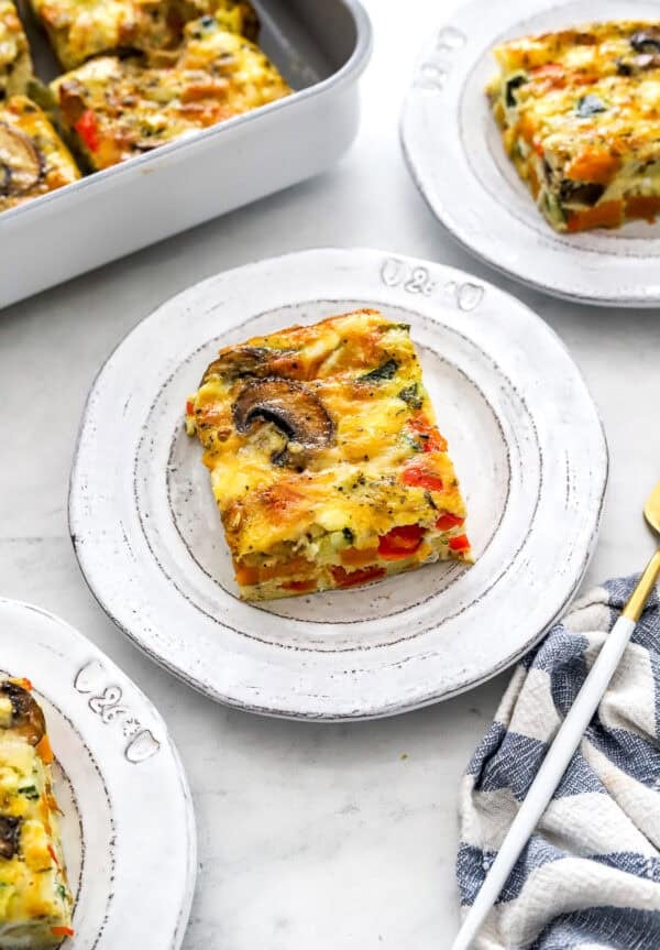 Pieces of baked egg and veggie casserole on plates.
