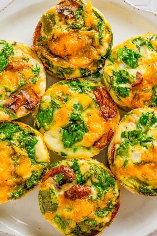 Egg white muffins filled with veggies and cheese on a plate.