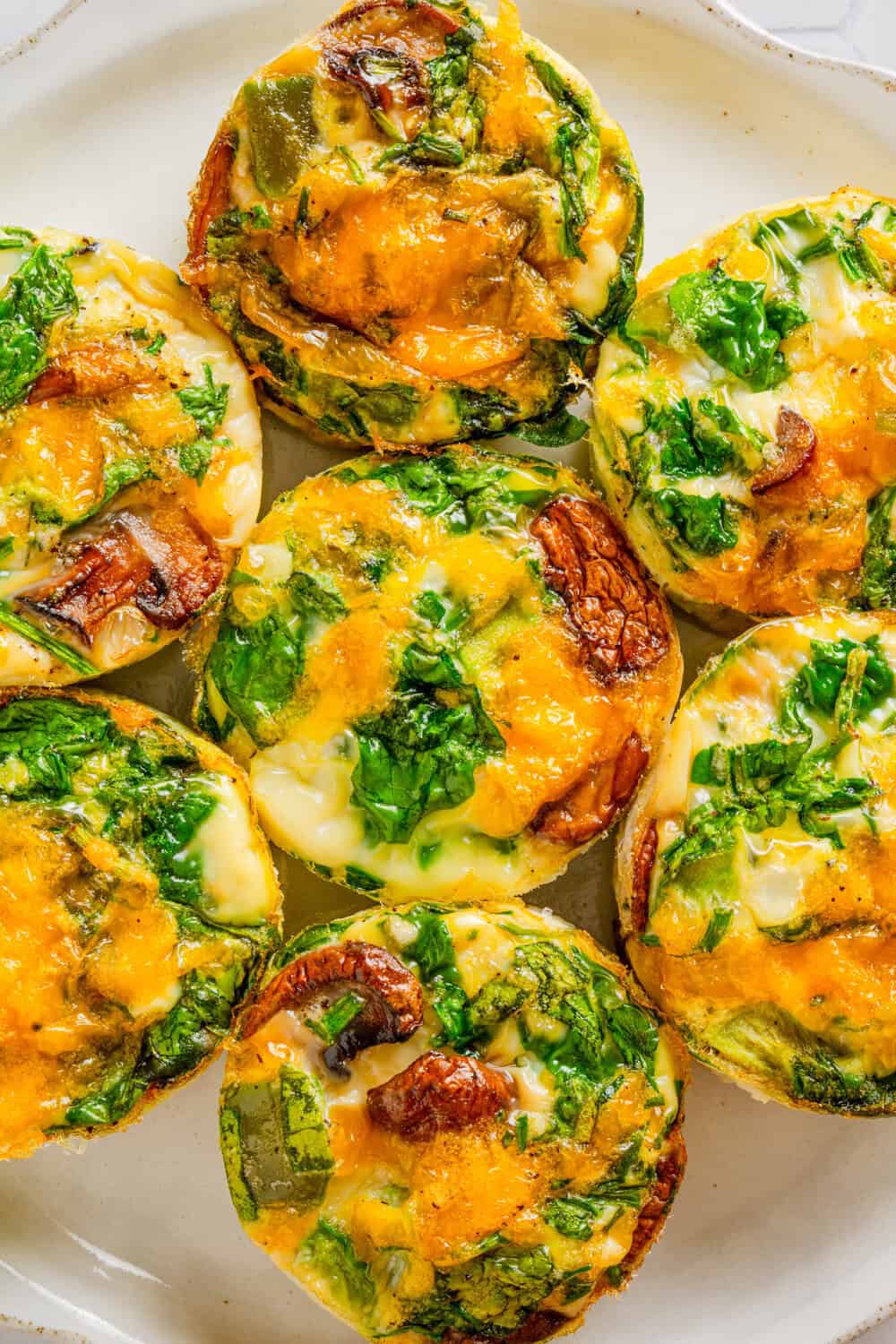Egg white muffins filled with veggies and cheese on a plate. 